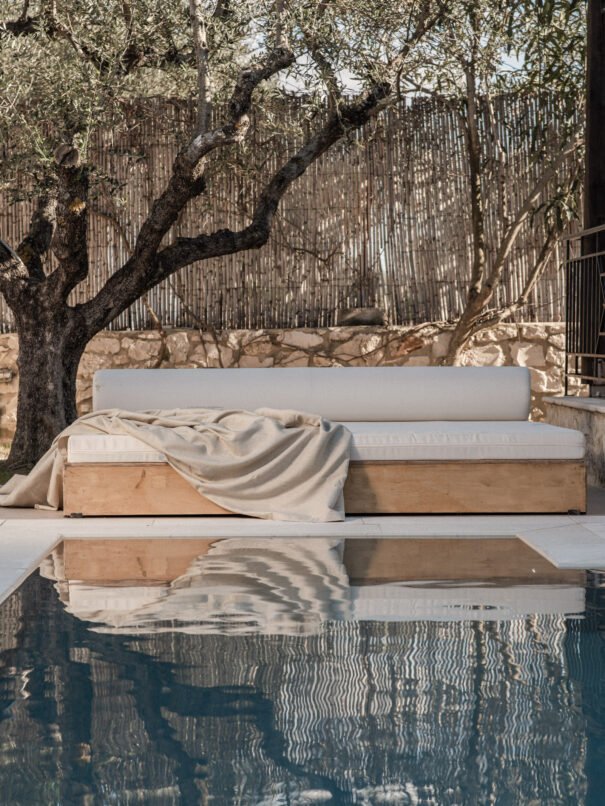 Beautifully landscaped outdoor area with sparkling pool, relaxing sunbed, and rustic olive tree
